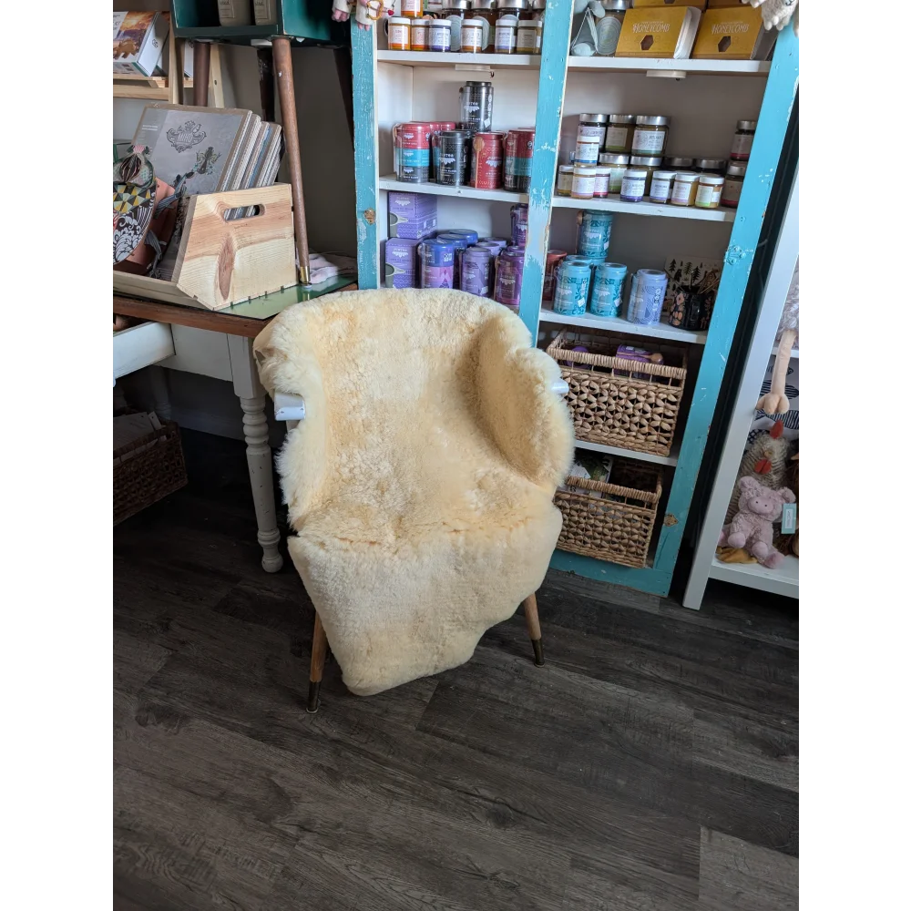 Cream-colored medical sheepskin washable chair cover draped over wooden armchair from angus oliver sheepskin rugs