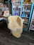 Cream-colored medical sheepskin chair cover draped over wooden chair by angus oliver for cozy comfort