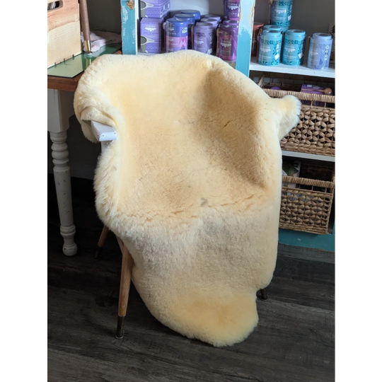 Cream-colored massive washable medical sheepskin draped over wooden chair frame by angus oliver