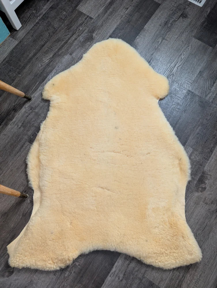 Cream-colored massive washable medical sheepskin rug by angus oliver with natural fluffy texture and irregular edges