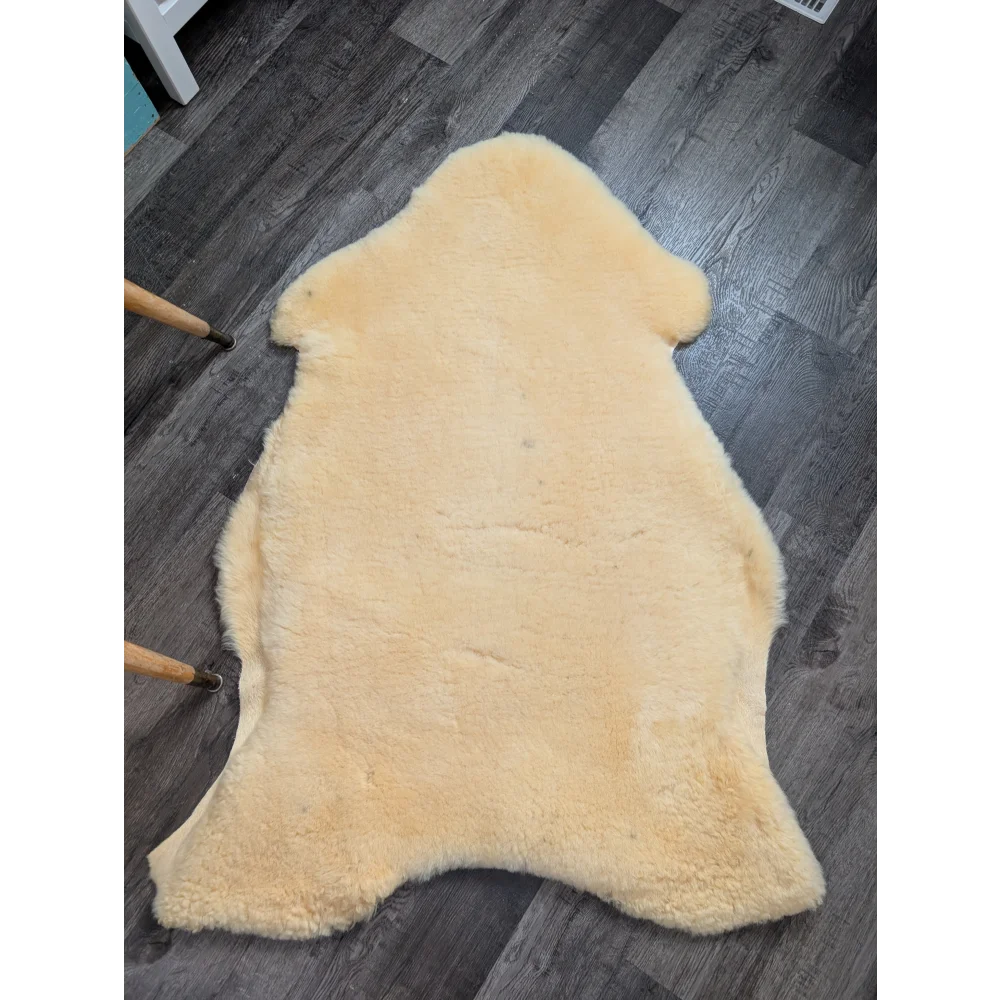 Cream-colored massive washable medical sheepskin rug by angus oliver with natural fluffy texture and irregular edges