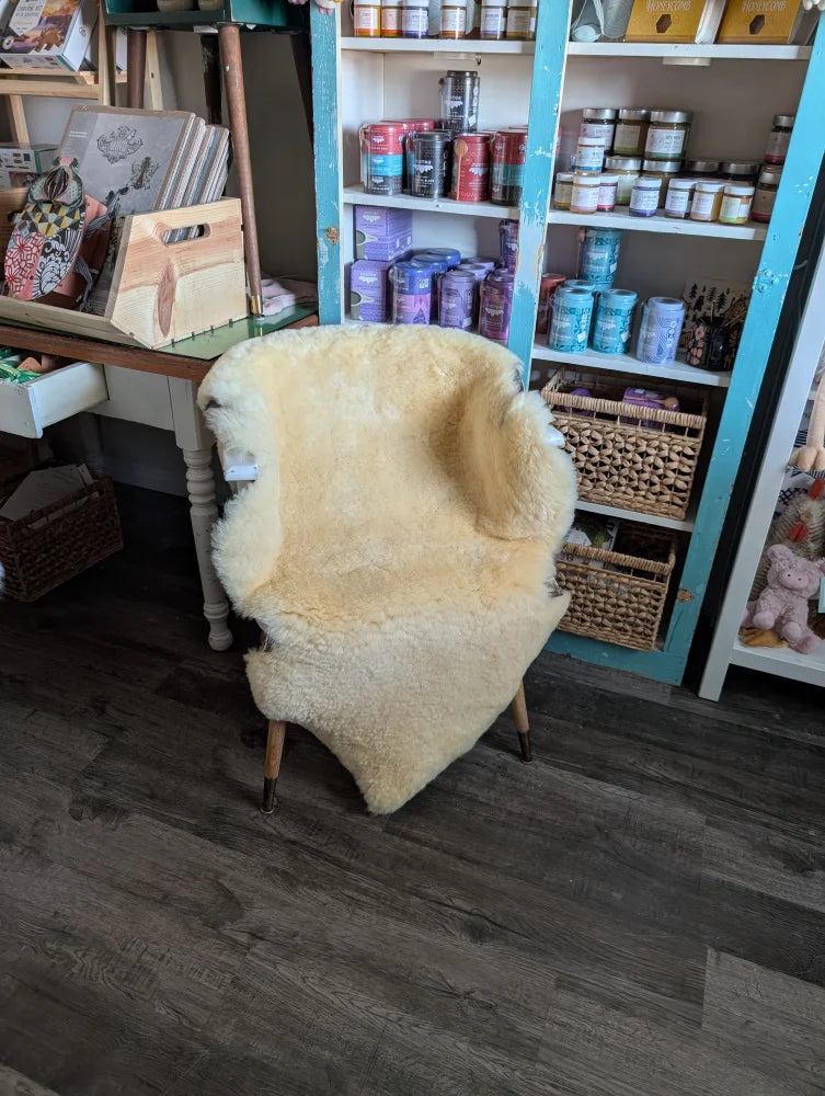 Cream-colored washable medical sheepskin chair with wooden legs by angus oliver for comfort and style