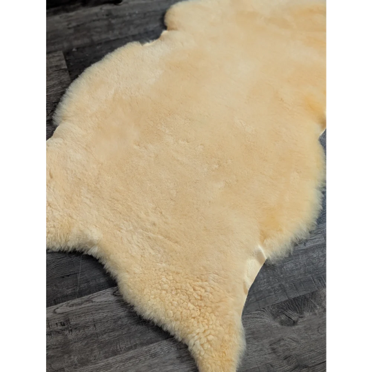 Cream-colored medical sheepskin rug with soft fluffy texture and natural edges by angus oliver 50 x 29 inches