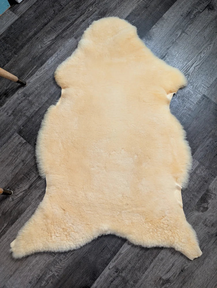 Cream-colored medical sheepskin rug with soft fluffy texture and natural edges by angus oliver for comfort and care