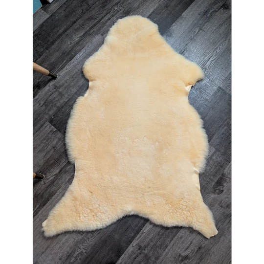 Cream-colored medical sheepskin rug with soft fluffy texture and natural edges by angus oliver for comfort and care
