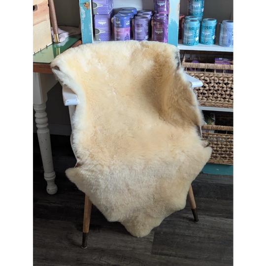 Cream-colored extra large washable medical sheepskin rug by angus oliver draped over a chair