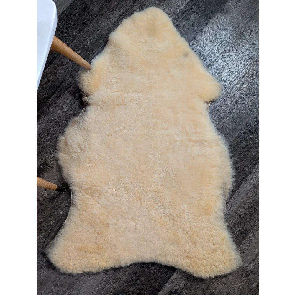 Cream-colored extra large washable medical sheepskin rug with soft fluffy texture and natural irregular edges by angus oliver