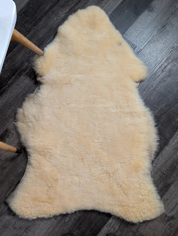 Cream-colored extra large washable medical sheepskin rug with soft fluffy texture and natural irregular edges by angus oliver