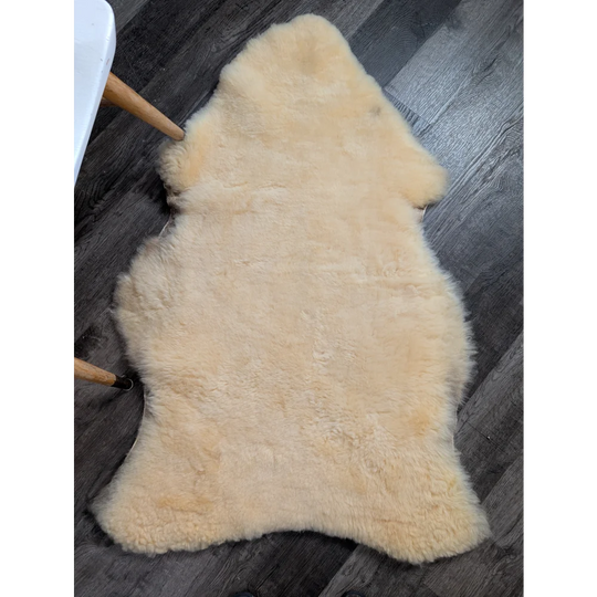 Cream-colored extra large washable medical sheepskin rug with soft fluffy texture and natural irregular edges by angus oliver