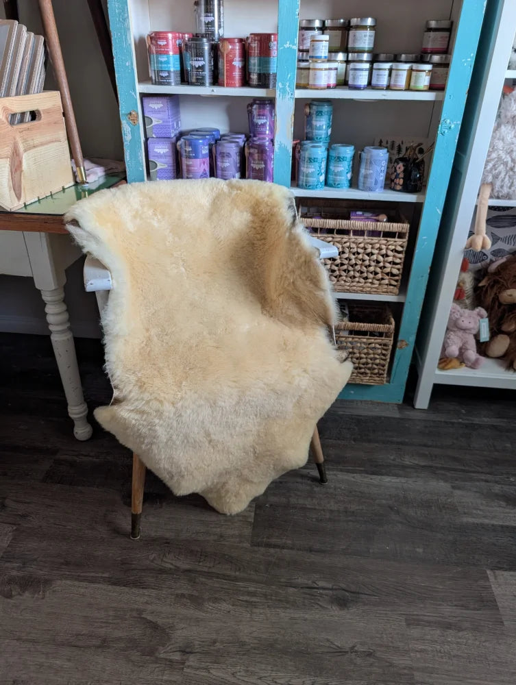 Cream-colored extra large washable medical sheepskin rug draped over chair by angus oliver