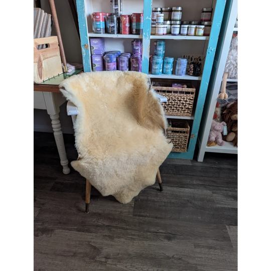 Cream-colored extra large washable medical sheepskin rug draped over chair by angus oliver