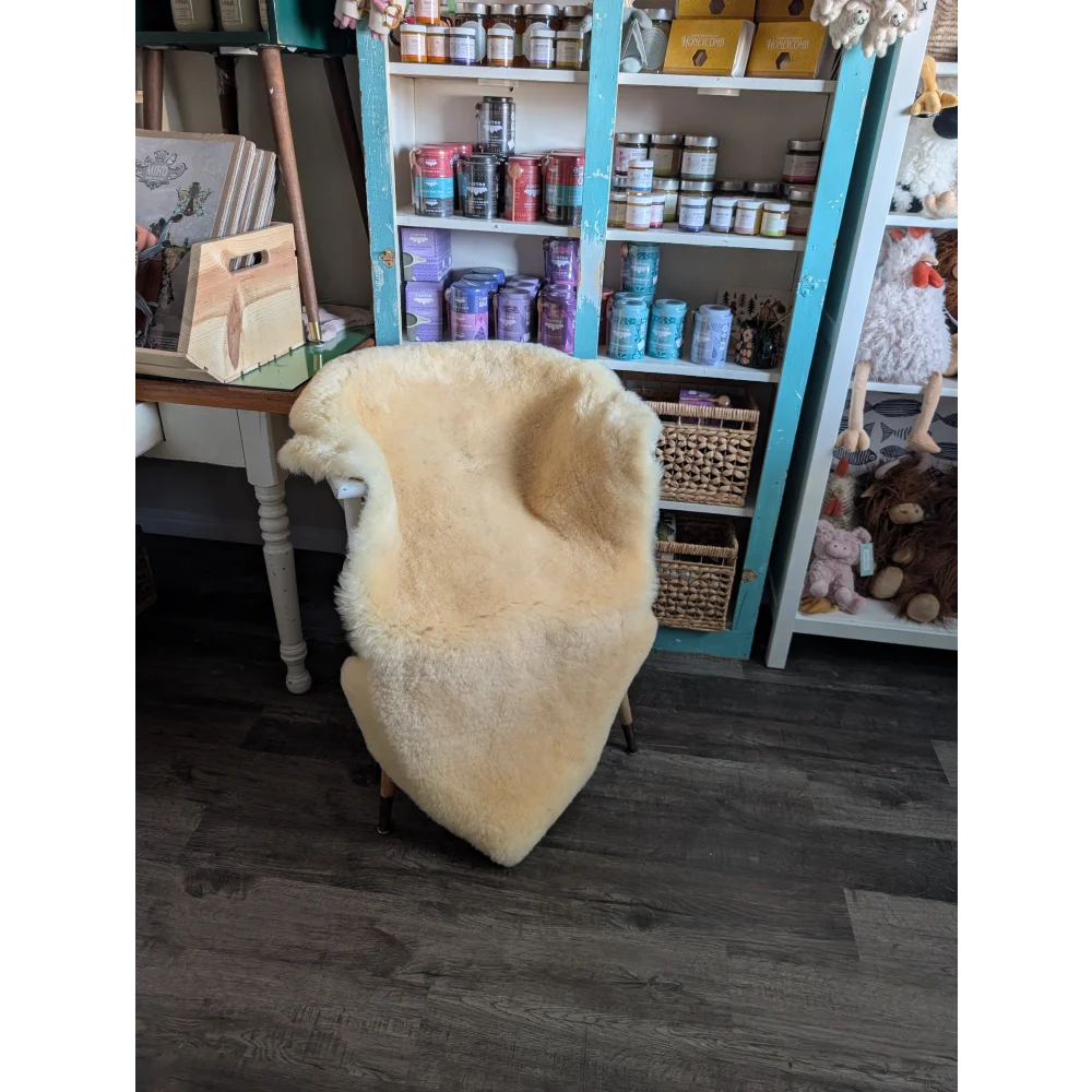 A cozy cream-colored medical sheepskin draped over a wooden frame from angus oliver sheepskin rugs and cowhide rugs