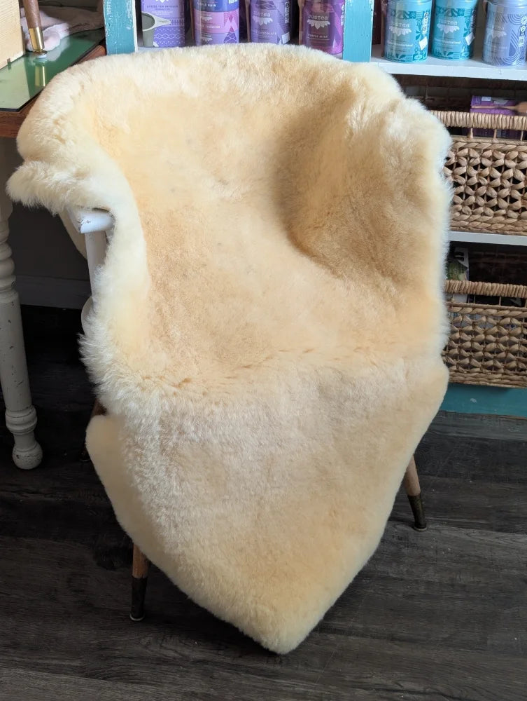 Cream-colored medical sheepskin chair cover draped over wooden chair from angus oliver washable sheepskin rugs