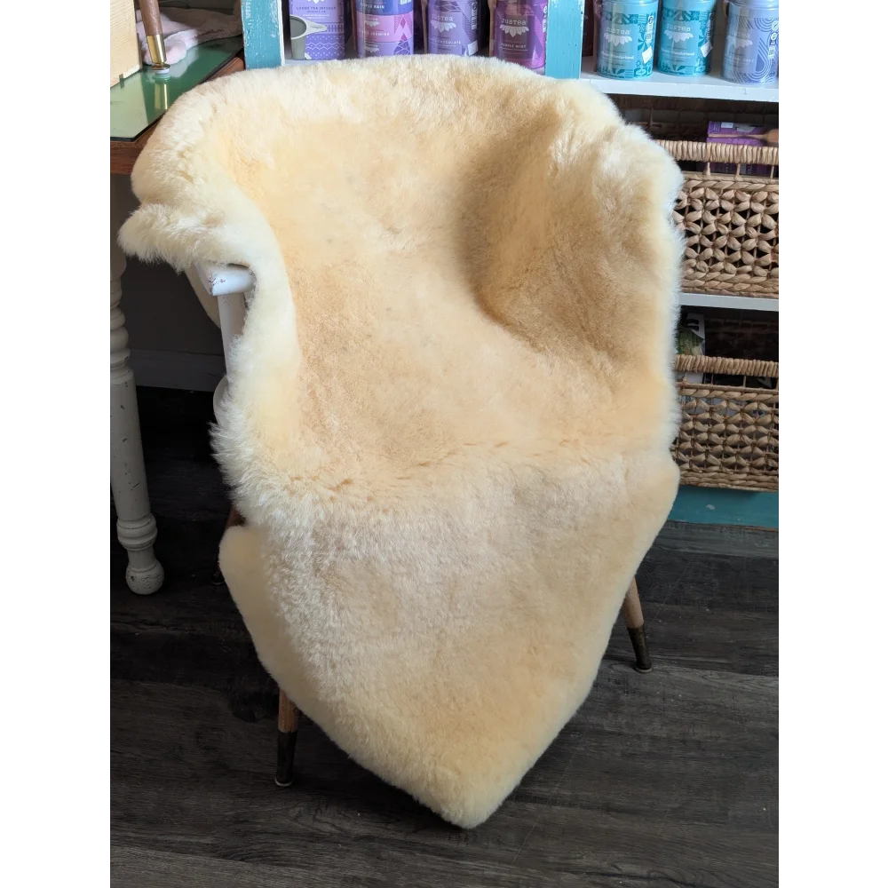 Cream-colored medical sheepskin chair cover draped over wooden chair from angus oliver washable sheepskin rugs