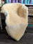 Cream-colored medical sheepskin chair cover draped over wooden chair from angus oliver washable sheepskin rugs