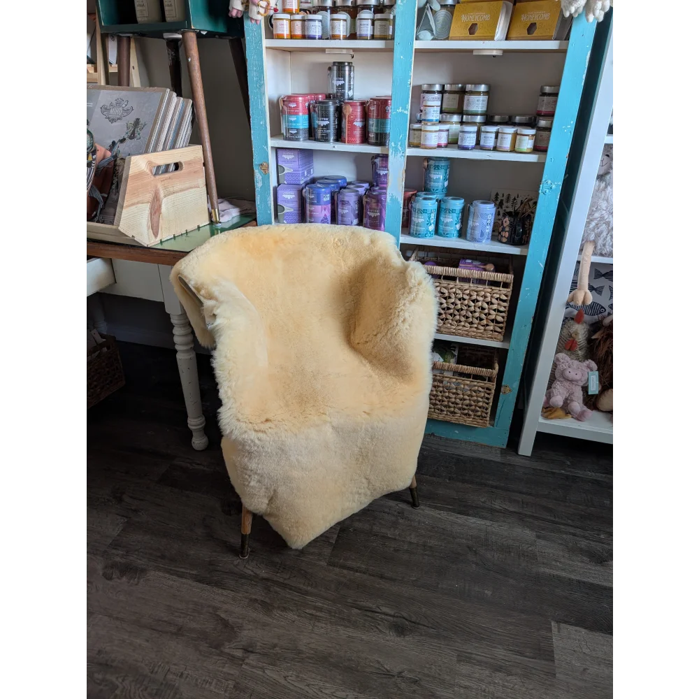Cream-colored extra large angus oliver armchair covered in washable medical sheepskin with wooden legs