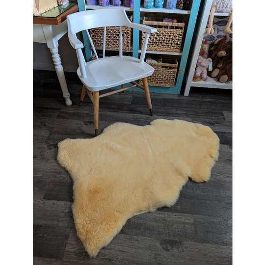 Cream-colored extra large washable medical sheepskin rug with natural fluffy texture and irregular edges by angus oliver