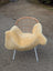 A cozy pale yellow medical sheepskin blanket draped over a modern wicker chair with white metal legs