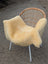 A cozy pale yellow extra large washable medical sheepskin throw draped over a modern rattan chair with white legs