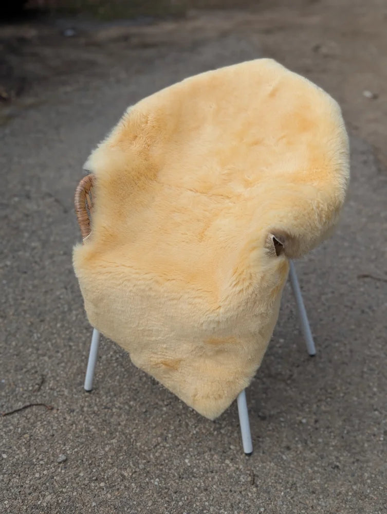 Cream-colored medical sheepskin chair with soft fluffy texture and white metal legs extra large washable design