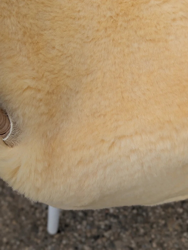 Cream-colored extra large washable medical sheepskin chair with soft fluffy texture and white metal legs
