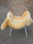 A soft creamy beige naturally spotted medical sheepskin blanket draped over a modern wicker chair with white legs