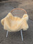 A cozy cream-colored medical sheepskin blanket naturally spotted draped over a wicker chair with white metal legs