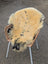 A cozy cream medical sheepskin with dark spots draped over a wicker chair naturally spotted and washable