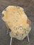 A soft creamy yellow medical sheepskin rug with naturally spotted dark speckles draped over a wicker chair