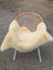 Cream-colored naturally spotted medical sheepskin blanket draped over wicker chair with white metal legs for medical use