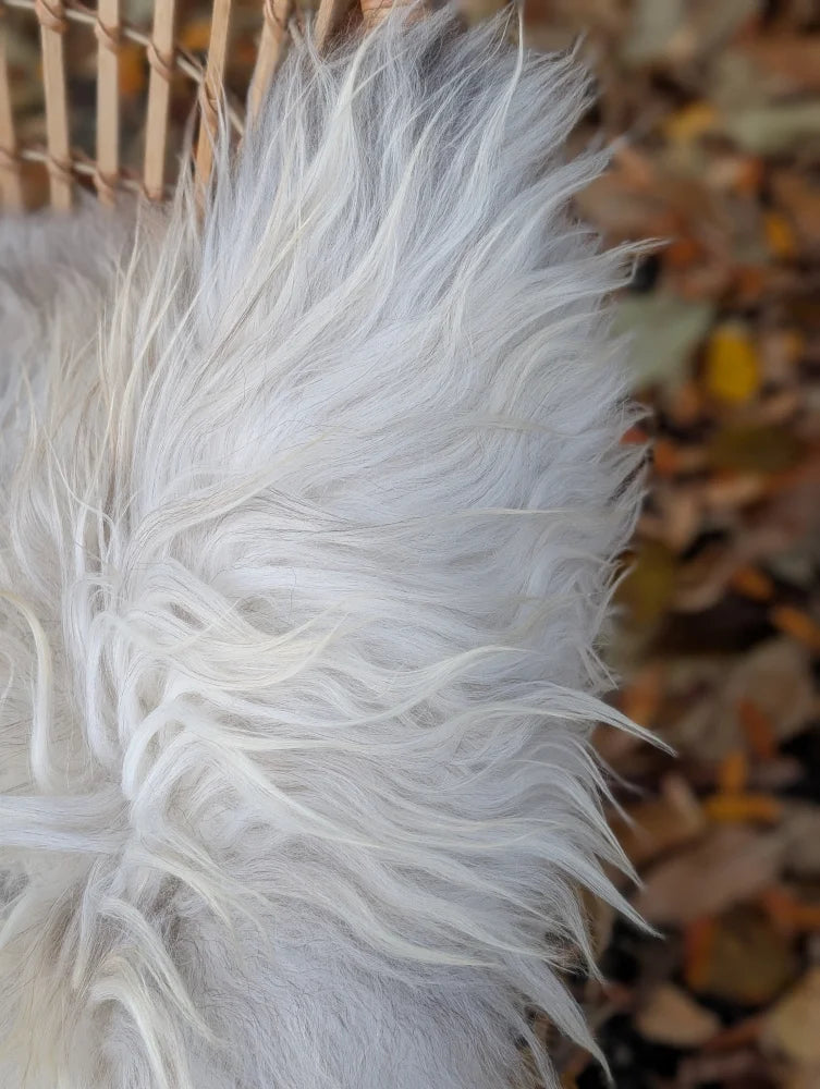 A fluffy white faux fur coat with long wool icelandic strands and plush texture in natural grey color