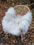 White fluffy wool icelandic sheepskin chair cover draped over woven wicker chair natural grey long wool