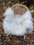 A cozy white wool icelandic sheepskin chair cover draped over a woven wicker chair for extra comfort