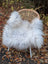 A fluffy wool icelandic sheepskin cover in natural grey draped over a wicker chair for cozy seating