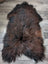 A massive natural dark rusty icelandic sheepskin rug with long wool icelandic in rich brown and black tones