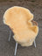 A cozy pale yellow extra large washable medical sheepskin draped over a modern wicker and metal chair frame