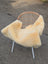 Cream-colored medical sheepskin throw draped over woven rattan chair with white metal legs naturally spotted design