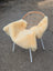 A soft creamy beige extra large washable medical sheepskin draped over a modern rattan chair with white metal legs