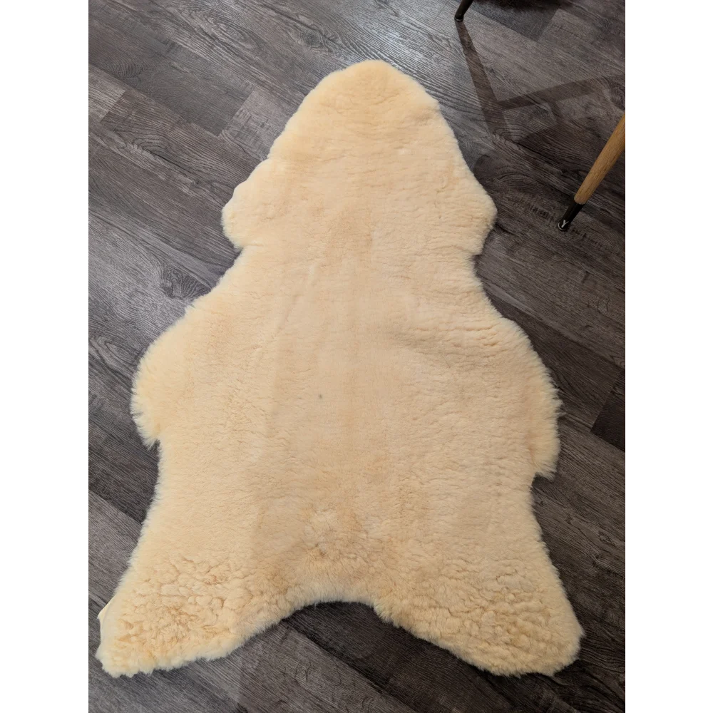 Cream-colored extra large medical sheepskin rug by angus oliver with soft fluffy texture and natural irregular edges