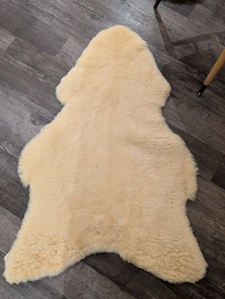 Cream-colored extra large medical sheepskin rug by angus oliver with soft fluffy texture and natural irregular edges