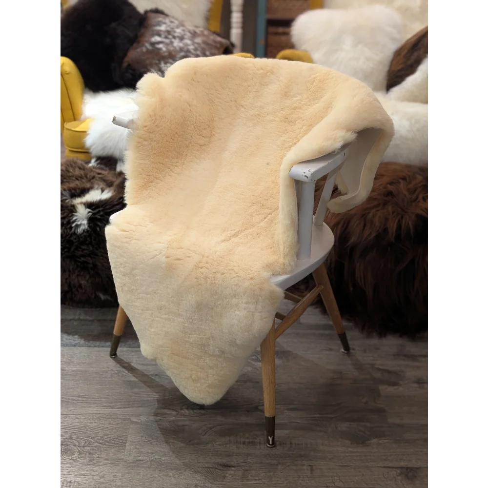 Cream-colored extra large med10 medical sheepskin throw draped over white wooden chair by angus oliver