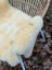 Cream-colored washable medical sheepskin chair cover with soft fluffy texture and naturally spotted fur pattern