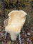 Cream-colored naturally spotted medical sheepskin rug draped over wicker chair with white metal legs, washable medical sheepskins