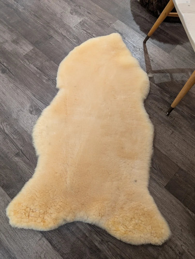 Cream-colored extra large medical sheepskin rug by angus oliver with soft fluffy texture and natural irregular edges