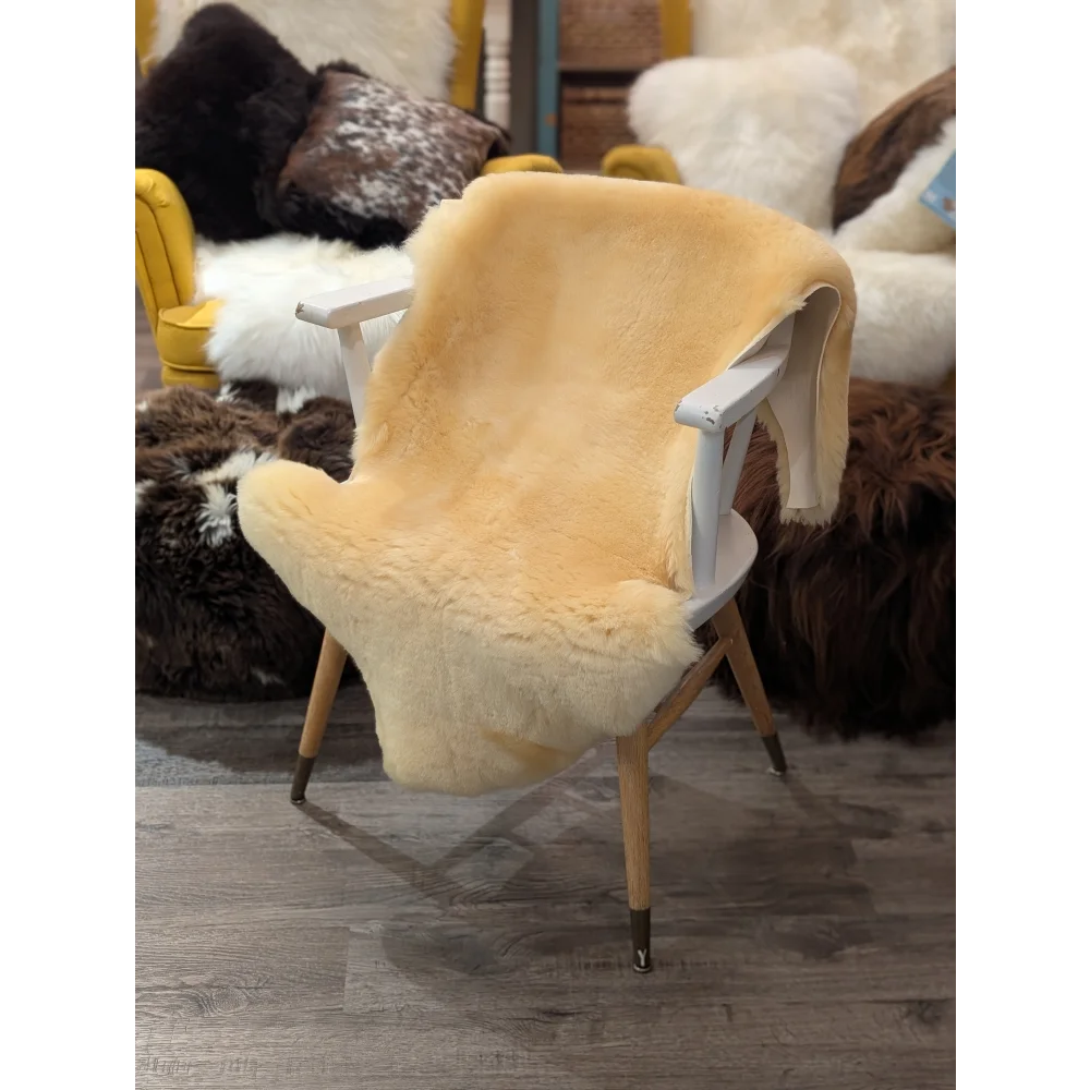 Cream-colored extra large medical sheepskin throw draped over white wooden chair by angus oliver