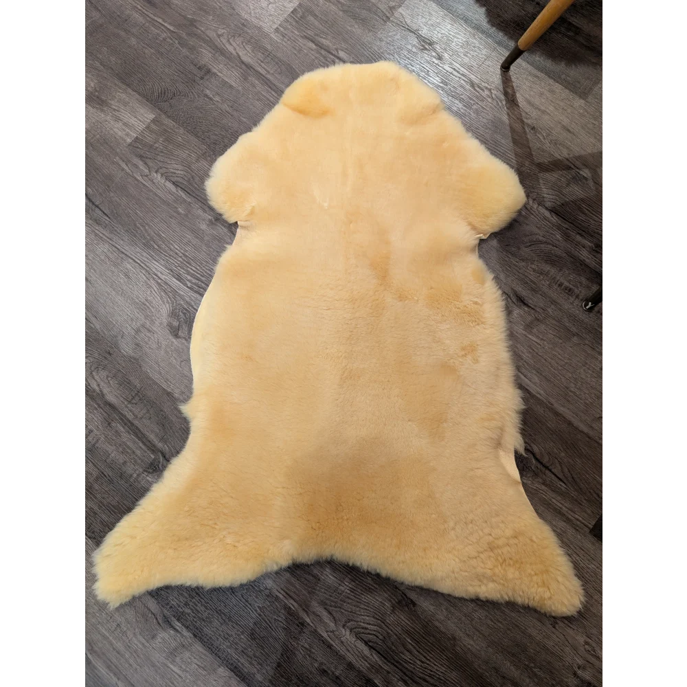 A soft pale yellow extra large med12 angus oliver medical sheepskin rug with natural fluffy texture and irregular edges