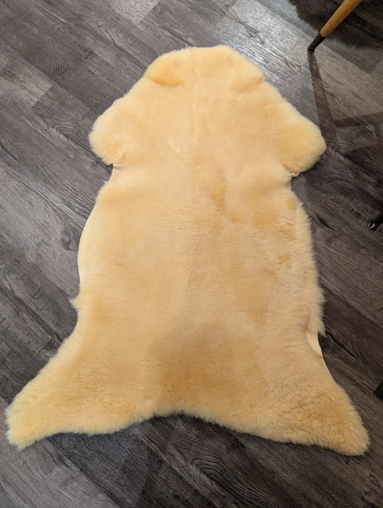 A soft pale yellow extra large med12 angus oliver medical sheepskin rug with natural fluffy texture and irregular edges