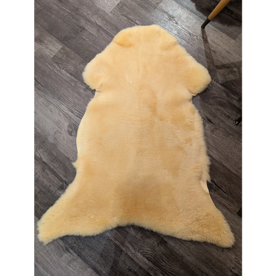 A soft pale yellow extra large med12 angus oliver medical sheepskin rug with natural fluffy texture and irregular edges