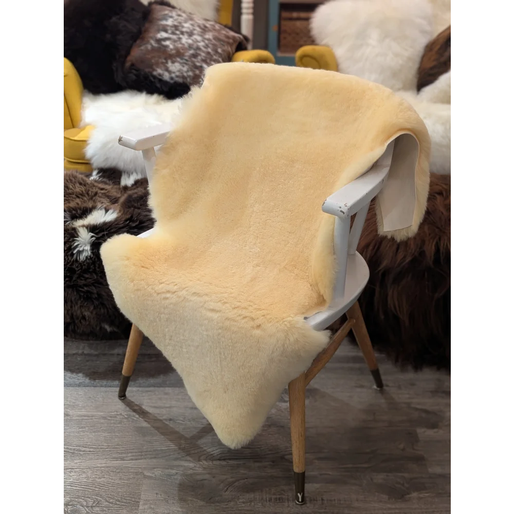 Cream-colored extra large medical sheepskin throw draped over white wooden chair by angus oliver