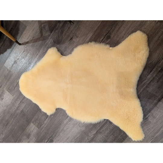 A soft pale yellow extra large medical sheepskin rug by angus oliver with a natural shape and plush texture